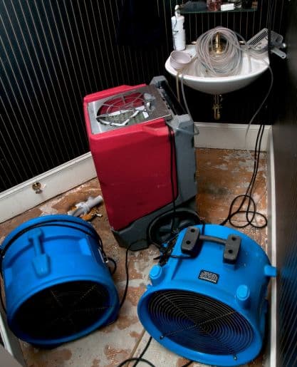 Professional dehumidifier and air mover in bathroom during sewage cleanup
